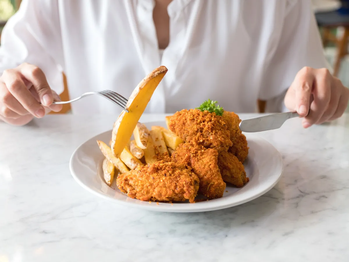 Persoană care mănâncă șnițele cu cartofi - Foto: Freepik (rol ilustrativ)