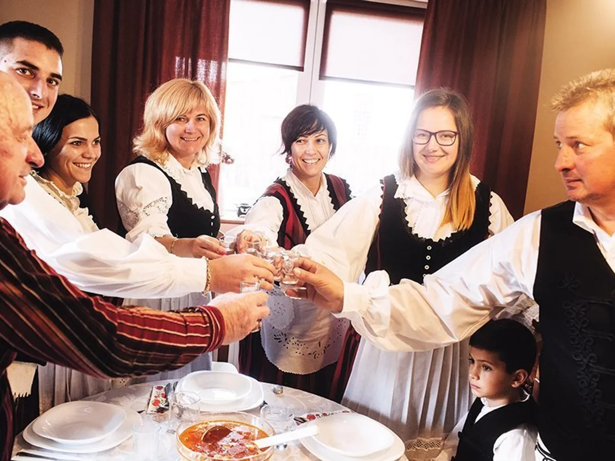 Maghiari ciocnind un pahar de palincă înainte de masă, acasă, în satul Lăzarea