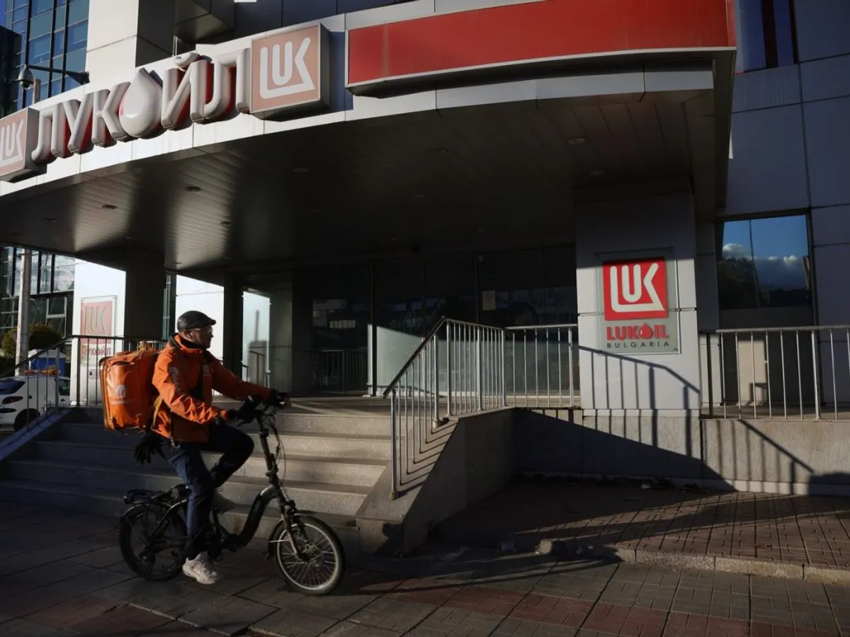 Un curier pedalează prin faţa sediului central al Lukoil din Sofia - Foto: Profimedia Images