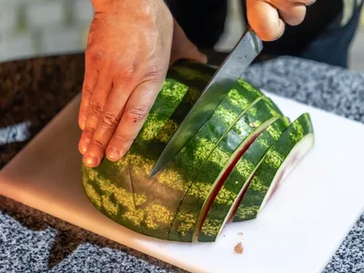Un bărbat taie un pepene verde - Foto: Magnific.com (Imagine cu rol ilustrativ)
