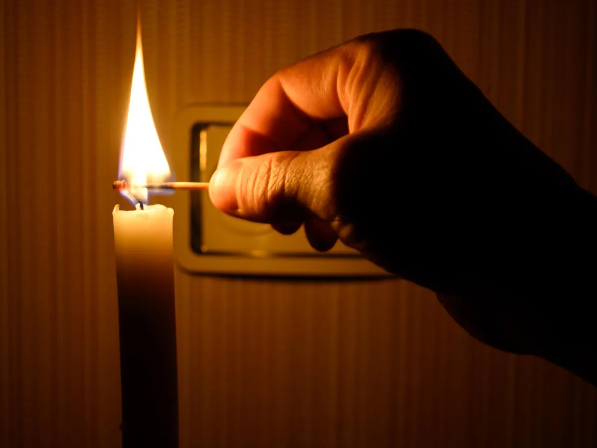 Persoană care aprinde o lumânare pe întuneric - Foto: Freepik (rol ilustriv)