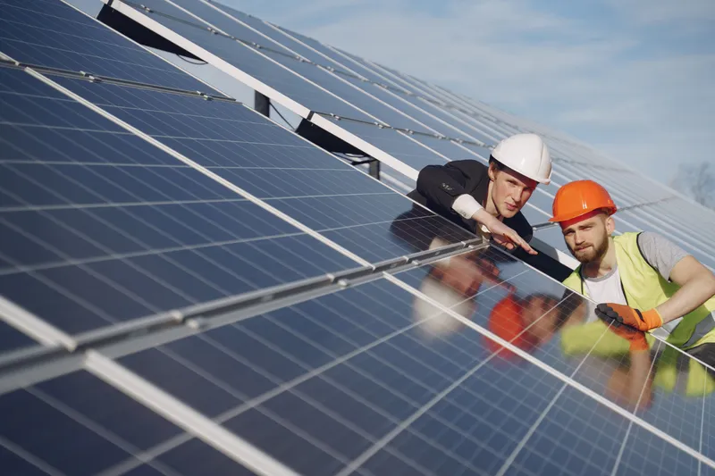 Doi bărbați așezați pe panouri fotovoltaice - Foto: Freepik (rol ilustrativ)