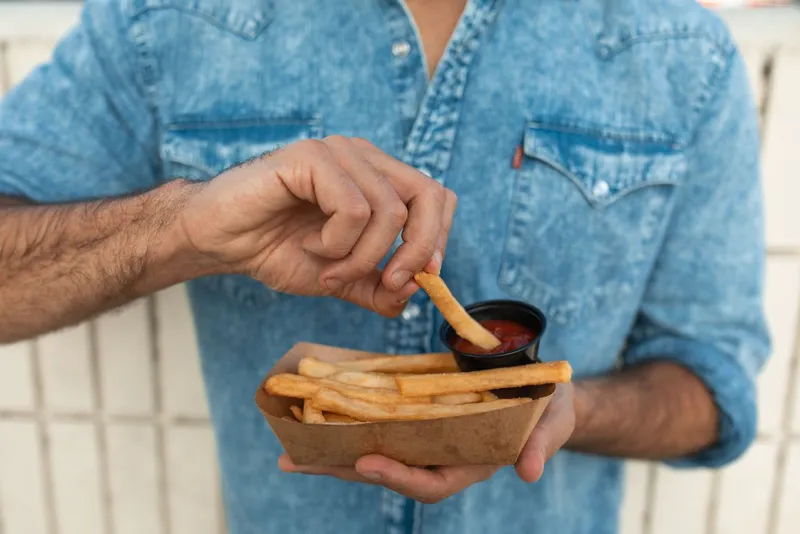Persoană care manancă cartofi prăjiți - Foto: Pexels (Imagine cu rol ilustrativ)
