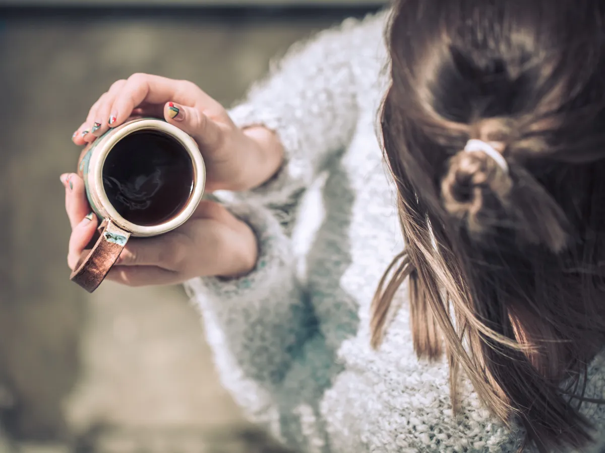 Femeie care ține în mână o ceașcă de cafea fierbinte - Foto: Freepik (rol ilustrativ)