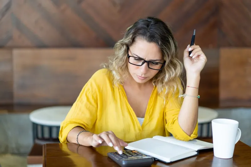 Femeie drăguţă calculând bugetul - Foto: Freepik/katemangostar