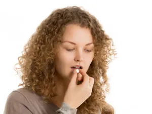 Tânără femei luându-şi medicamentele compensate - Foto: Freepik/yanalya