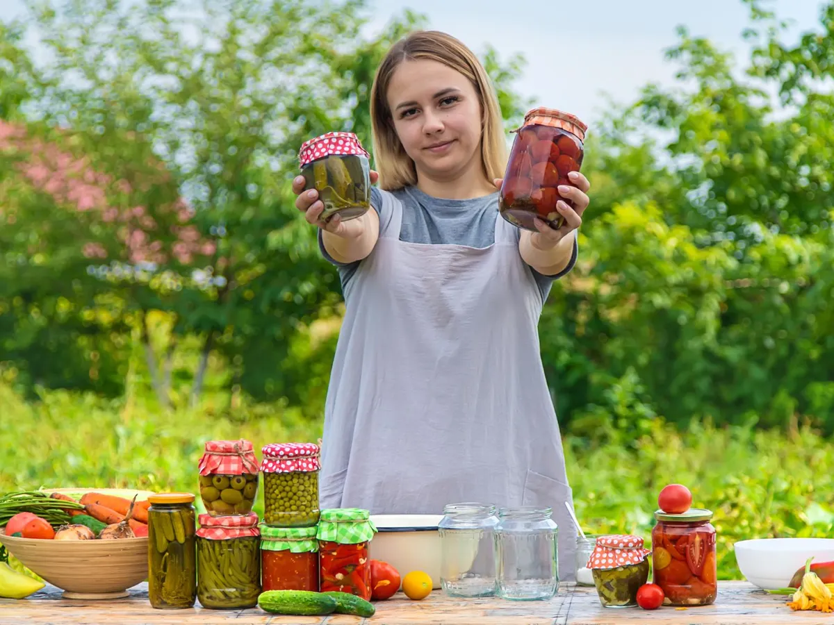 O femeie conservă legume în borcane - Foto: Magnific.com (Imagine cu rol ilustrativ)