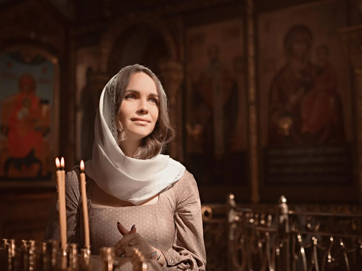 Tânără femeie din Biserica Ortodoxă aprinde lumânări - Foto: Magnific.com (Imagine cu rol ilustrativ)
