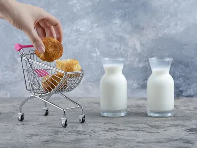 Femeie punând într-un coşuleţ generic de decumpărături budincă de paste şi lapte - Foto: Magnific.com/azerbaijan_stockers