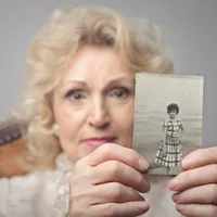 O bătrână care ține în mână o fotografi veche - Foto: Freepik