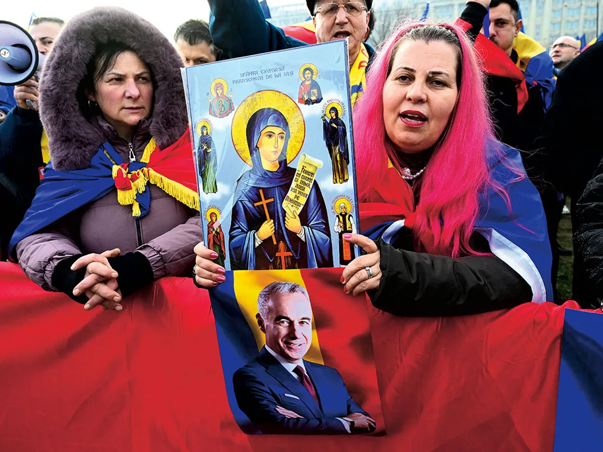 O femeie ține în mână un afiș cu icoane și un portret al candidatului de extremă dreapta la președinție, Călin Georgescu, în fața Curții Constituționale a României la București, pe 10 ianuarie 2025 - Foto: Profimedia Images