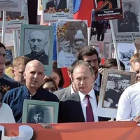 VLADIMIR PUTIN, cu fotografia tatălui său, care a luptat în Armata Roșie în timpul celui de-Al Doilea Război Mondial. Imaginea a fost răspândită de organul de propagandă al Rusiei, Sputnik.