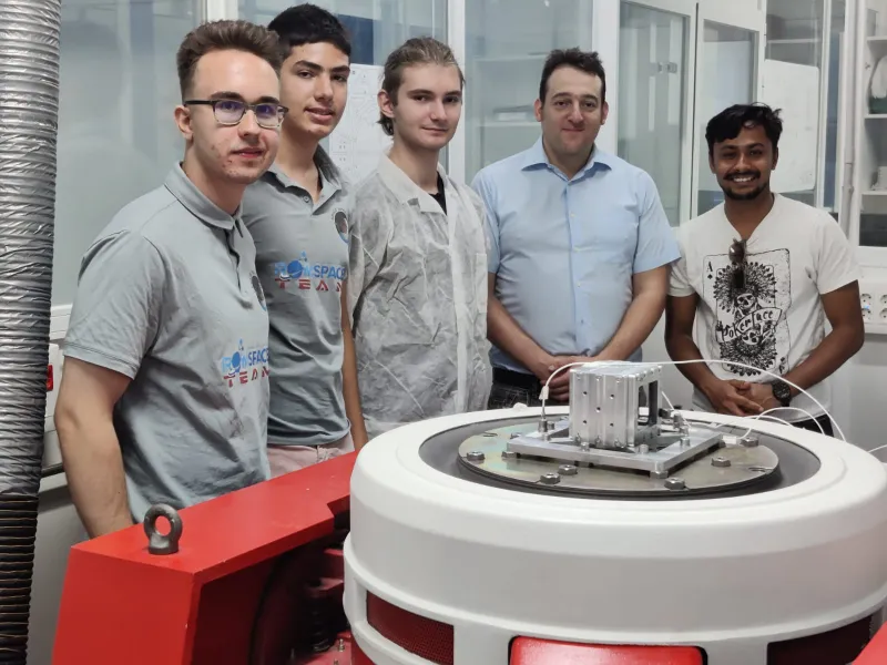 Alexandru Luchianov, Filip Bușcu, David Constantinescu (RomSpace), alături de Felix Paez (AMSAT) și Saurav Paudel (Orion Space) în laboratorul Institutului de Microgravitație de la UPM. În centru, satelitul ROM-2 la finalul testelor. / Foto: RomSpace