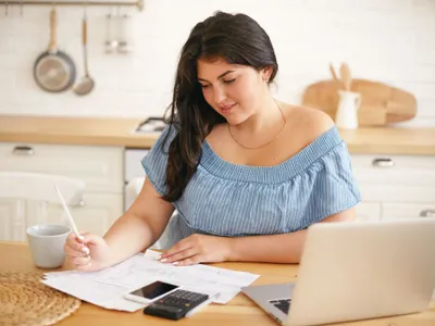 Tânără femeie calculând ce face cu economiile ei personale - Foto: Freepik/shurkin_son