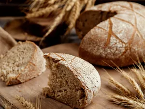 Felie de pâine integrală organică, așezată pe un fund de lemn, în stil rustic - Foto: Freepik/KamranAydinov