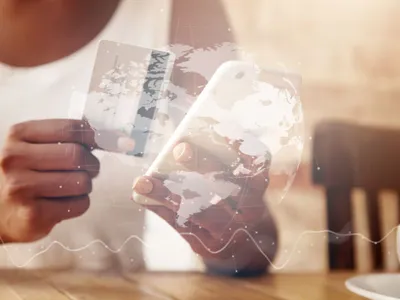 Femeie cu card de credit şi smartphone, văzută printr-un display transparent cu globul planetar - Foto: Magnific.com/wayhomestudio
