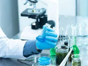 Persoană ţinând în mână un flacon de laborator - Foto: Pexels/Chokniti Khongchum