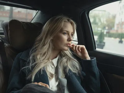 Femeie în costum de haine, pe bancheta din spate a unei maşini - Foto: Pexels/Tima Miroshnichenko