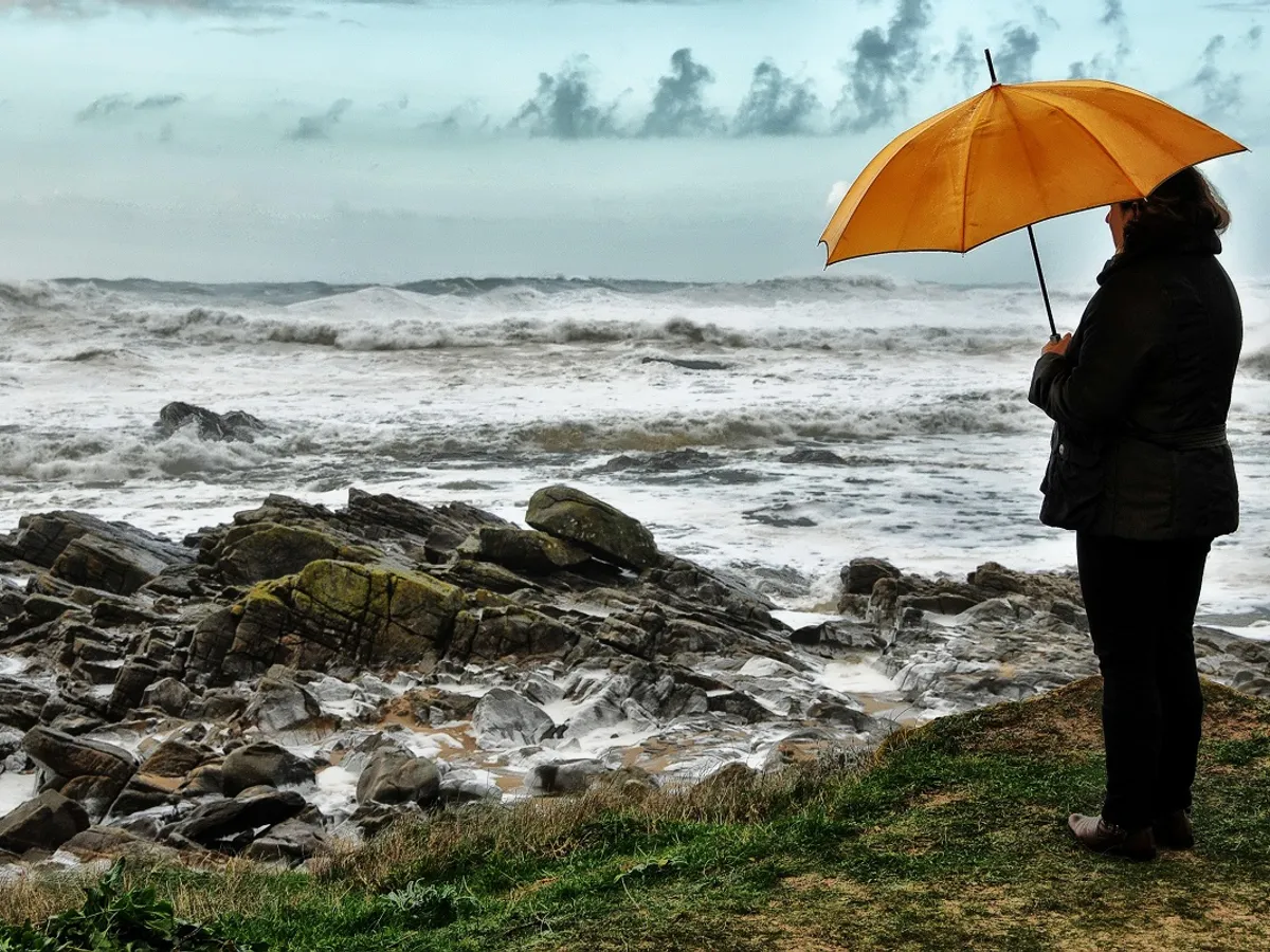 Femeie cu ubrală stând la malul oceanului: Foto - Pixabay (cu rol ilustrativ)