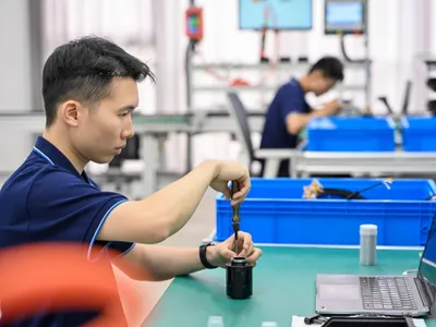 Doi tehniicieni chinezi asamblează componente ale unui robot umanoid, pe linia-pilot de asamblare - Foto: Profimedia Images
