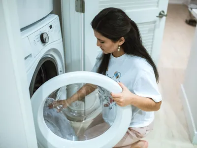 Femeie care deschide mașina de spălat rufe - Foto: Pexels (Imagine cu rol ilustrativ)