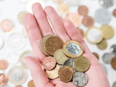 Monede de diferite tipuri, ţinute în mână, de o femeie - Foto: cottonbro studio