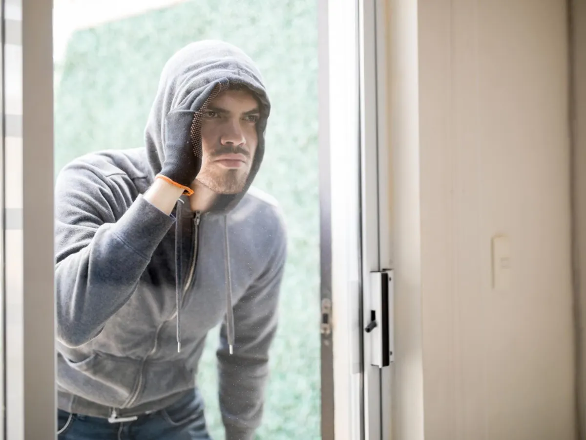 Un hoț privește pe fereastră - Foto: Freepik (rol ilustrativ)