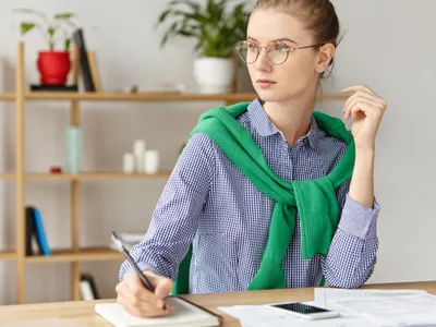 Femeie de afaceri îmbrăcată casual făcând calcule - Foto: Freepik/wayhomestudio