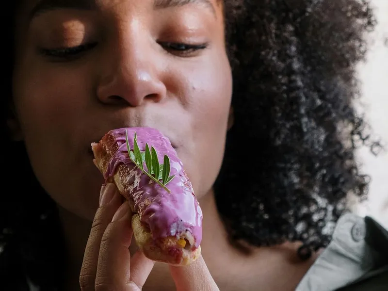 Femeie mâncând un ecler - Foto: Pexels/cottonbro studio