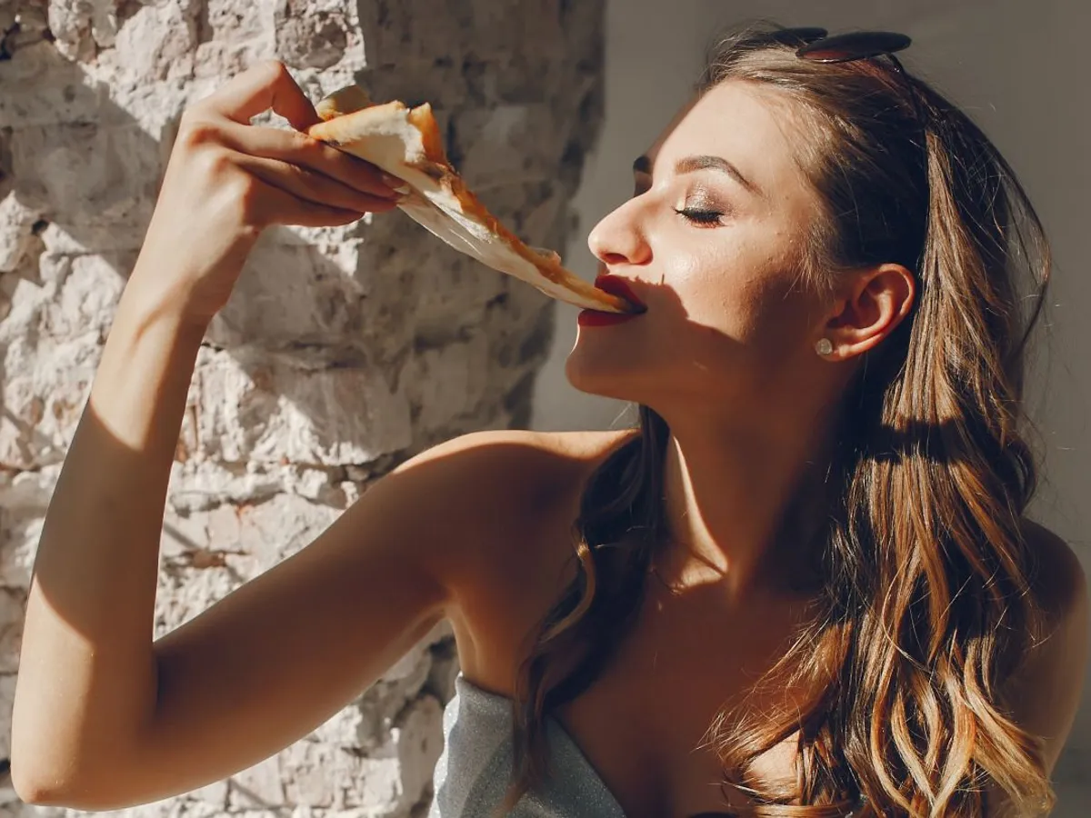Tânără femeie mâncând pizza - Foto: Magnific/prostooleh