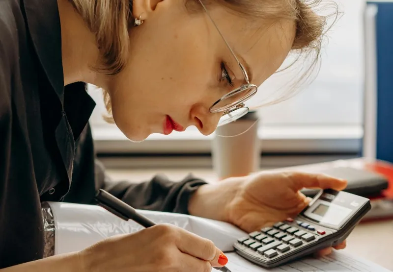 Femeie concentrată, făcând calcule complicate - Foto: Pexels/Mikhail Nilov