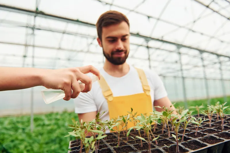 M&acirc;na unei femei care udă plantele cu suport negru &icirc;n m&acirc;ini - Foto: Freepik (Imagine cu rol ilustrativ)