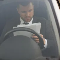 Șofer cu documentele în mână aflat la volanul mașinii - Foto