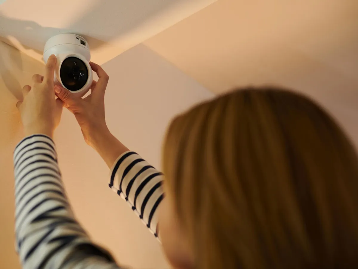 Femeie instalând o cameră de securitate - Foto: Magnific.com (Imagine cu rol ilustrativ)