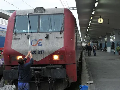 Un bărbat curăţă faţa locomotivei trenului care pleacă din Salonic, spre Sofia - Foto: Profimedia Images