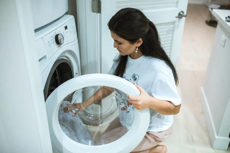 Femeie care pune rufele &icirc;n mașina de spălat - Foto: Pexels (Imagine cu rol ilustrativ)
