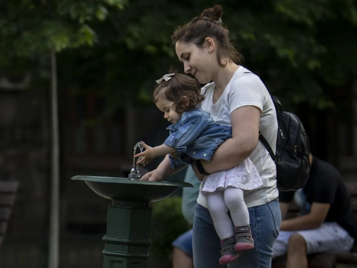 Femeie cu copil lângă o ţâşnitoare, în Bucureşti - Foto: Profimedia Images