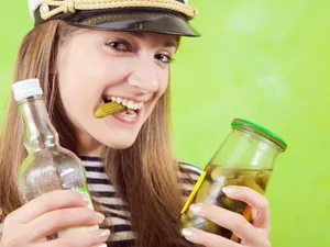 Femeie frumoasă care mănâncă un castravete și are în mână un borcan - Foto: Freepik