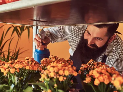 Bărbat care stropește florile - Foto: Magnific.com (Imagine cu rol ilustrativ)
