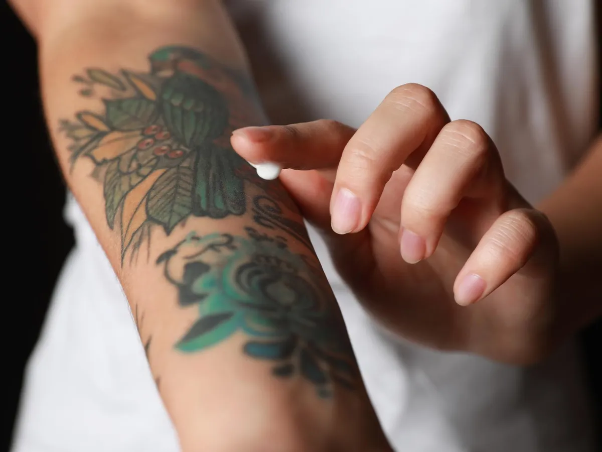 Femeie care se dă cu o cremă pe tatuaj -Foto: Freepik (rol ilustrativ)
