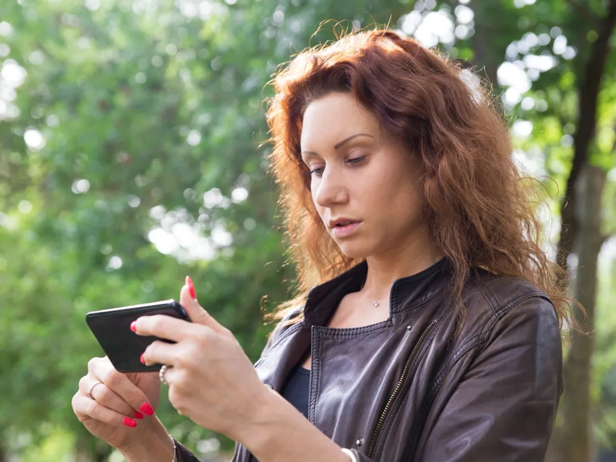 Femeie citind ceva în smartphone - Foto: Magnific.com/katemangostar