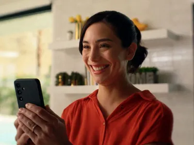 Femeie râzând şi urmărind ceva în smartphone - Foto: Profimedia Images