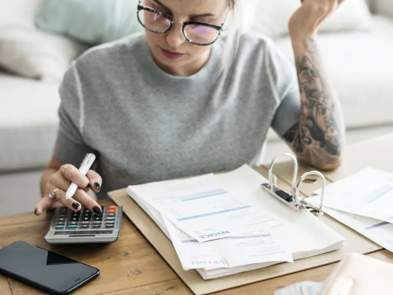 Femeie atentă făcând calcule privind banii pe care i-a acumulat la Pilonul II - Foto: Freepik/rawpixel.com