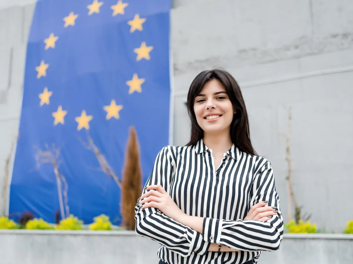 Portretul unei femei zâmbitoare cu steagul Uniunii Europene - Foto: Freepik (rol ilustrativ)