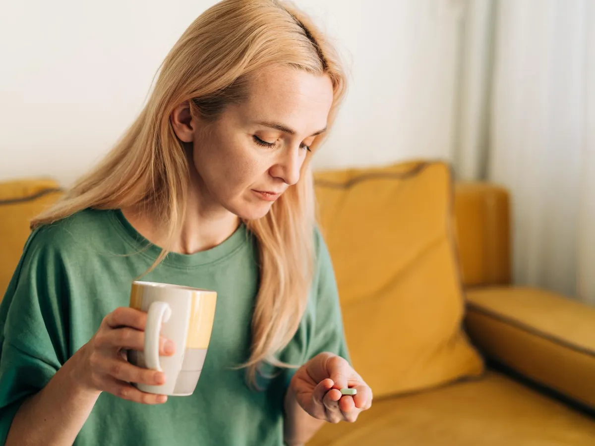 Femeie care bea cafea și administrează un medicament - Foto: Freepik (rol ilustrativ)