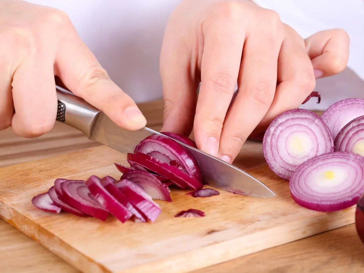 Persoană care taie o ceapă - Foto: Freepik (Imagine cu rol ilustrativ)