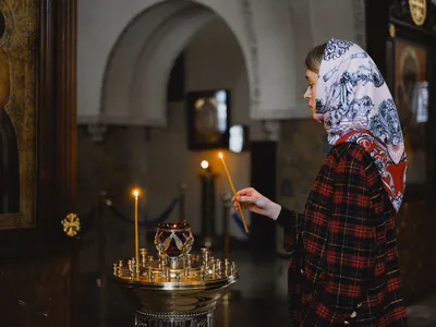 Femeie aprinzând o lumânare într-o biserică - Foto: Pexels (Imagine cu rol ilustrativ)