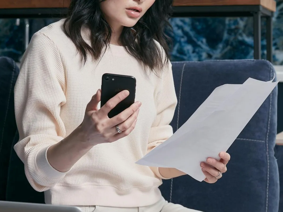 Femeie făcând calcule, cu telefonul în mână - Foto: Pexels/Mikhail Nilov