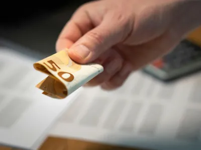 Bărbat ţinând în mână o bancnotă de 50 de euro - Foto: Pexels/Jakub Zerdzicki