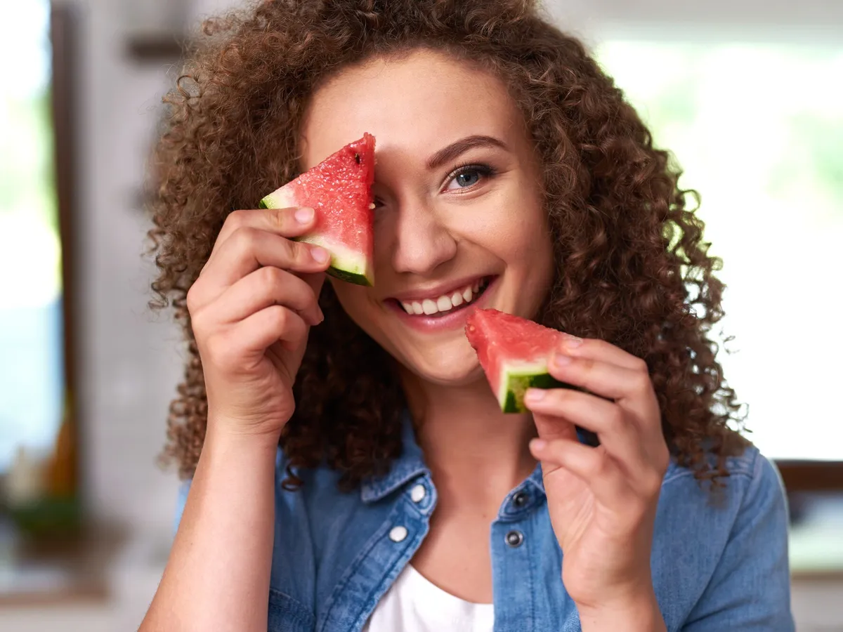 O femeie frumoasă care ține două bucăți de pepene - Foto: Freepik
